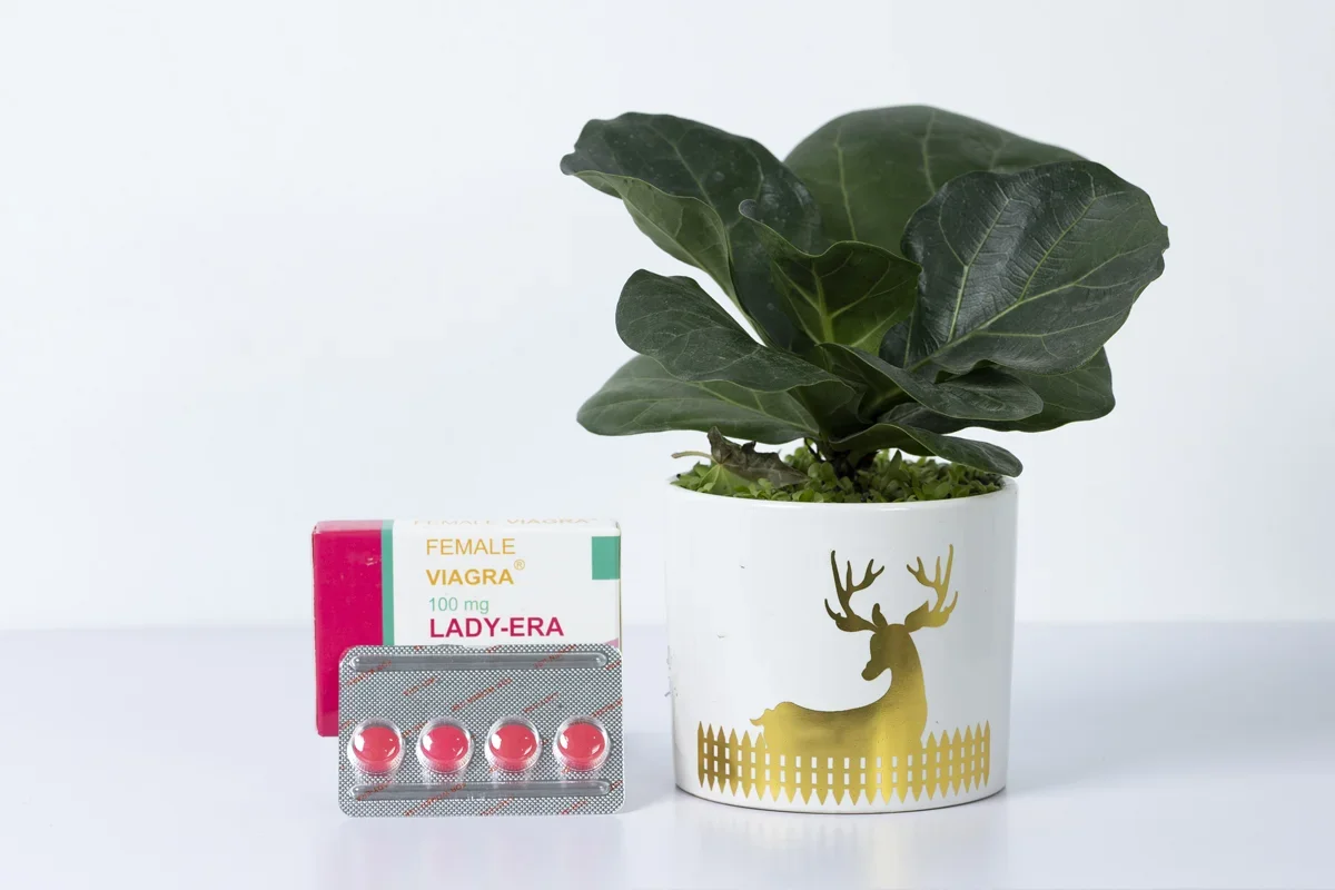 Cận cảnh thuốc kích dục nữ dạng viên Female Viagra Lady-Era 100mg vỉ 4 viên màu hồng đặt cạnh chậu cây trên nền trắng