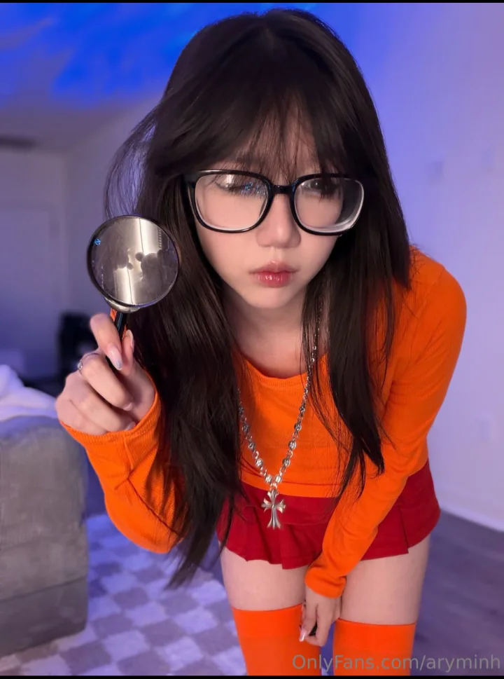Ảnh arynminh onlyfan leak, cô gái cầm kính lúp mặc áo khoác cam và quần lót ngắn đỏ.